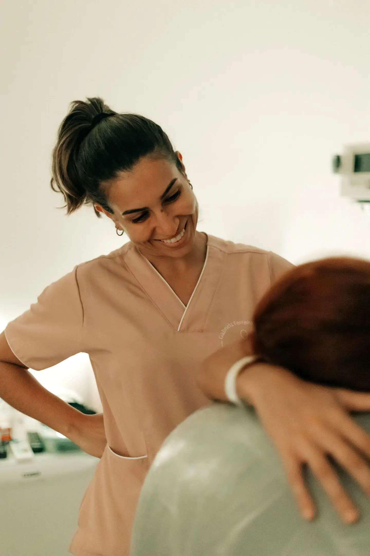 Gabriela sorrindo, de pijama cirúrgico rosa, durante um atendimento